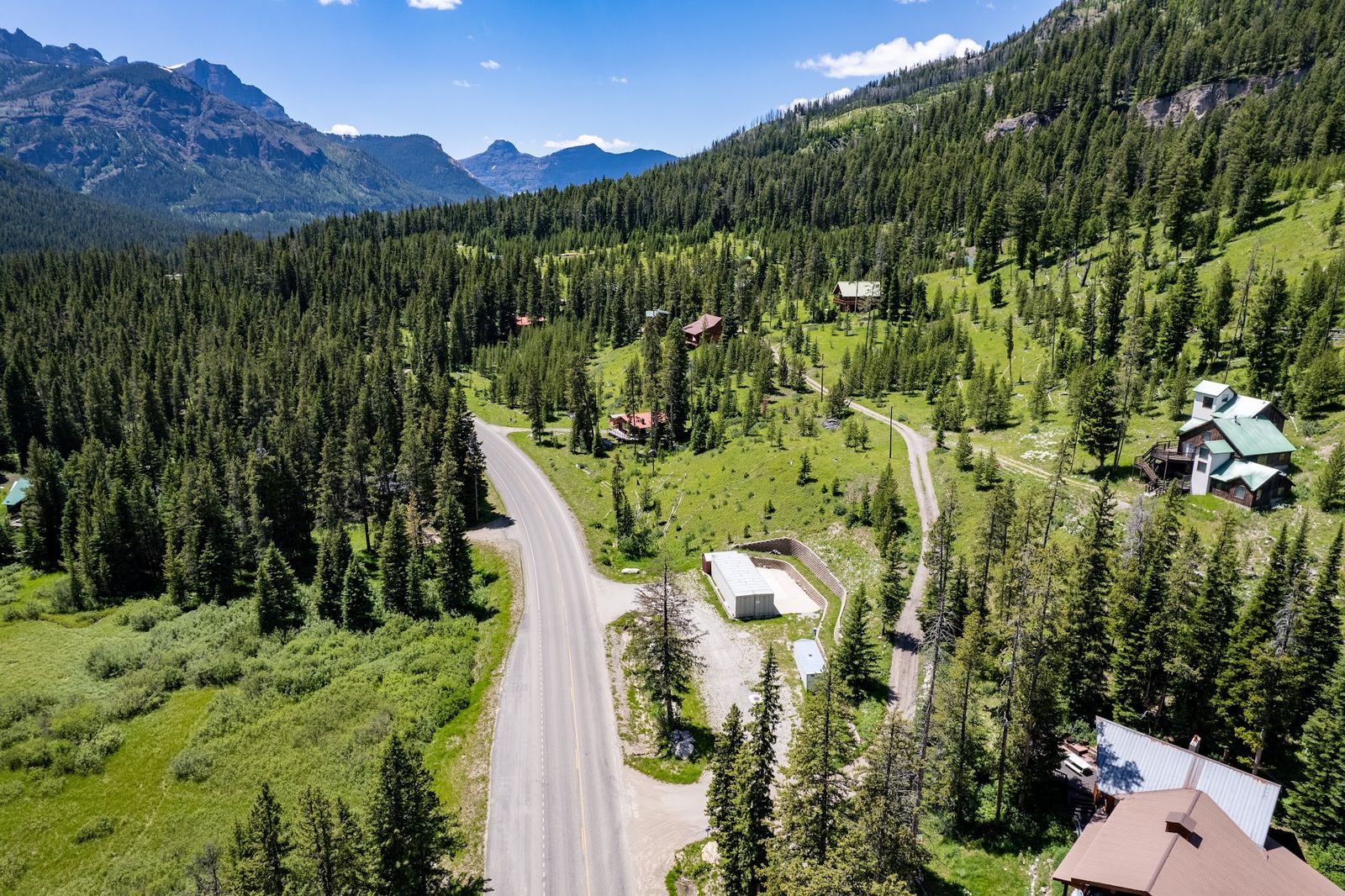 Aerial view of forested mountain parcels with cabins below rocky peaks