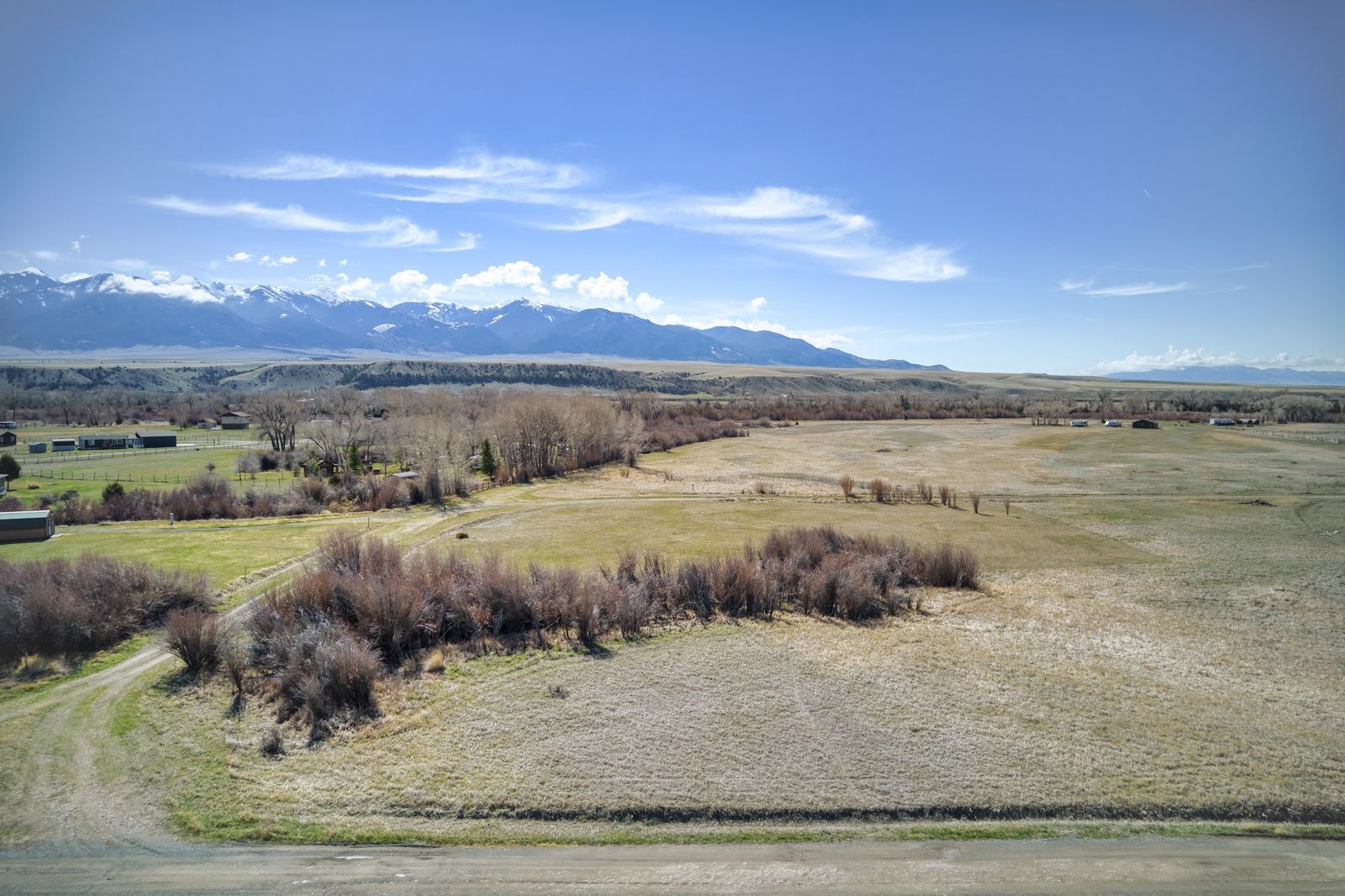 Aerial view of open valley pasture with snow-capped peaks on the horizon